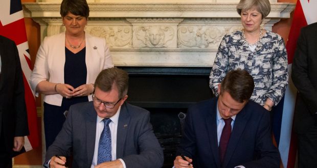 PM Theresa May  stands next to DUP leader Arlene Foster  as Jeffrey Donaldson and  Gavin Williamson sign agreement. Photograph: Reuters