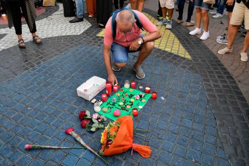 A man displays a candle next to flowers and a message for victims on August 18. Photograph: Javier Soriano/AFP/Getty Images
