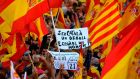 A protester holds a sign reading ‘Being Catalan is a pride, being Spanish is an honour’ as others wave Spanish and Catalan Senyera flags during a pro-unity demonstration in Barcelona. Photograph: Lluis Genelluis/AFP/Getty Images