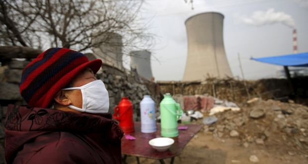 A woman wearing a mask reacts at her garden which is located next to the chimneys of a coal-fired power plant in Shijiazhuang, Hebei province, China. Photograph: Reuters/Kim Kyung-Hoon 