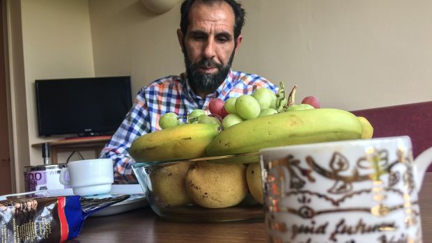 Nazim gazes at the plate of fruit in front of him, and begins to cry: ‘I want to give a banana to my child’. Photograph: Sally Hayden