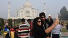 Visitors take  selfies in front of the Taj Mahal in Agra, India, today. India is to restrict the number of daily visitors to the 17th century monument  in an effort to preserve it. Photograph: Dominique Faget/AFP/Getty Images
