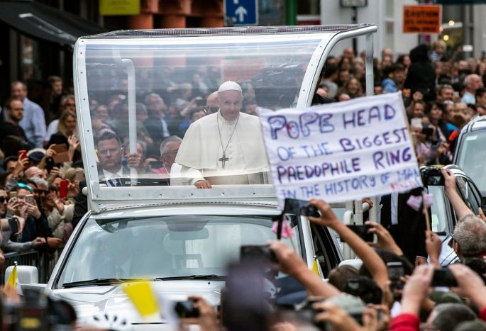 A protester holds up a banner while Pope Francis travels through the streets of Dublin. Photograph: Will Oliver/EPA
