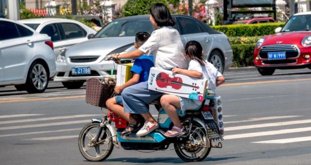 A woman rides her scooter with two children in Huaxian county in China’s central Henan province. China appears set to end its two-child policy. Photograph:  AFP/Getty Images