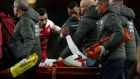Sporting Lisbon’s Nani grasps the hand of the  injured Danny Welbeck after  the Arsenal striker was stretchered off with  a serious leg injury during the Europa League game at Emirates stadium. Photograph: Richard Heathcote/Getty Images