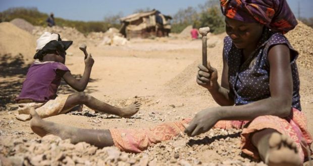 A child and a woman break rocks at a cobalt pit in Lubumbashi in the DRC. Photograph: Junior Kannah/AFP/Getty Images