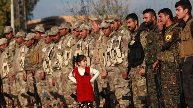 A young girl stands in front of fighters from the Syrian Democratic Forces in the Kurdish-controlled city of Qamishly in northeastern Syria, on December 3rd. They were attending the funeral of a fellow fighter killed in the town of Hajin during battles against the Islamic State terror group. Photograph: Delil Souleiman/AFP/Getty Images