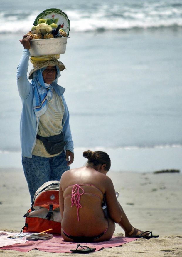 The photograph used on the cover of Lessenich’s book. A vendor walks past a foreign tourist enjoying the sun at Kuta beach, on Bali island in December 2006. File photograph: Sonny Tumbelaka/AFP Photo/Getty Images