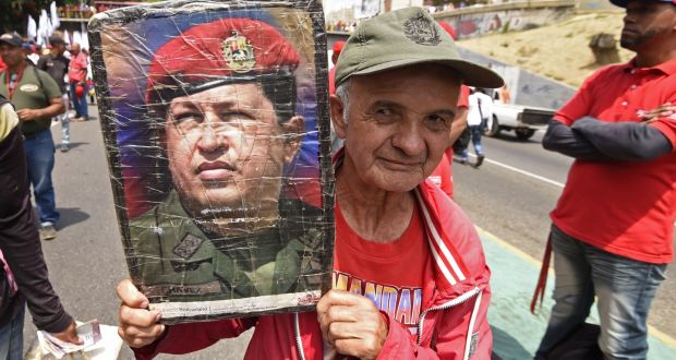 A supporter of Venezuelan president Nicolas Maduro displays a picture of late leader Hugo Chavez during a rally on May Day in Caracas. Photograph: Juan Barreto/AFP/Getty Images