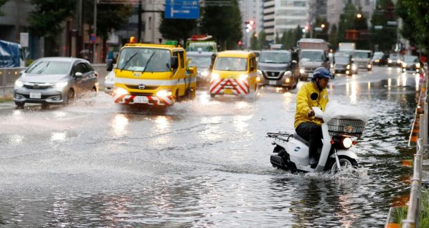 A man rides a moped through a flooded street due to a typhoon in Tokyo on Monday. Photograph: Kyodo News via AP