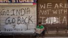 A Kashmiri man in front of closed shops covered with graffiti in the  commercial hub of Srinagar city centre. Photograph: Yawar Nazir/Getty 