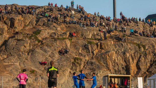 Fans watch from the top of a cliff that serves as a grandstand as players on the team G-44 (blue) celebrate a goal against IT-79 (pink). Photograph: Kieran Dodds/New York Times