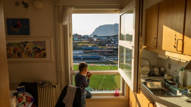 Nikki Jensen watches a match from his family’s kitchen above the soccer stadium in Sisimiut, Greenland. Photograph: Kieran Dodds/New York Times