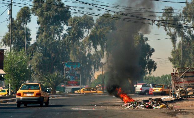 Motorists pass by a fire lit by anti-government protesters in Baghdad on Sunday. Photograph: Khalid Mohammed/AP