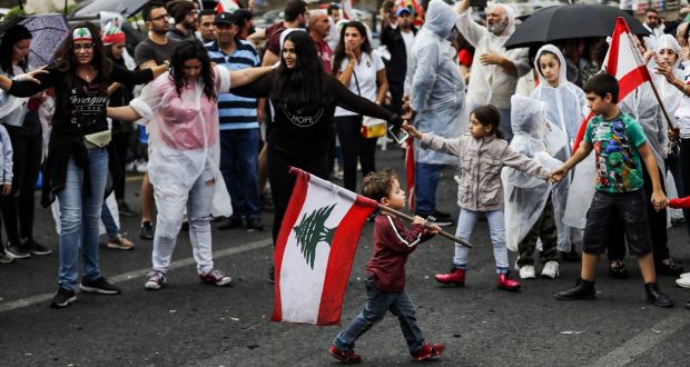 A  boy walks with a Lebanese flag past protesters in Zouk Mosbeh, north of Beirut, on Thursday. Photograph: Joseph Eid/AFP via Getty Images