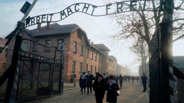 Holocaust survivors walk below the gate with its inscription ‘Work sets you free’ after a wreath-laying at the death wall at the memorial site of the former German Nazi death camp of Auschwitz during ceremonies on Monday to commemorate the 75th anniversary of the camp’s liberation. Photograph: Janek Skarzynski/AFP via Getty Images