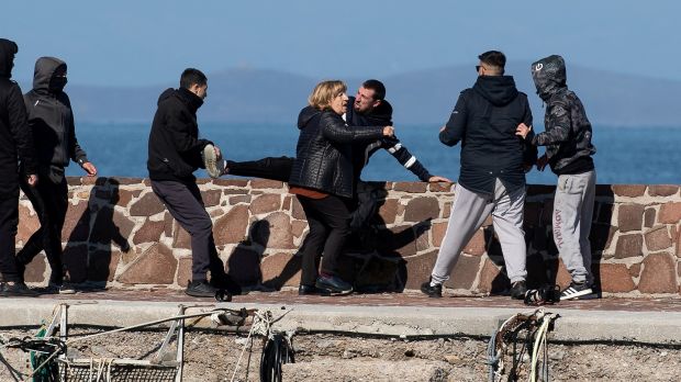 Locals, who prevent migrants on a dinghy from disembarking at the port of Thermi, beat a journalist, as a woman tries to stop them, on the island of Lesbos, Greece on Sunday. Photograph: Reuters/Stringer