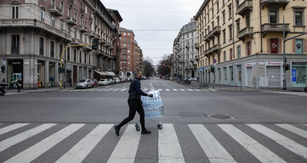 A man, pulling a trolley filled with bottles of water, crosses a deserted street on in Milan, Italy on Thursday. Photograph: Emanuele Cremaschi/Getty Images)