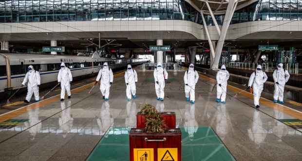 Staff members spray disinfectant at Wuhan Railway Station in Wuhan in China’s central Hubei province. Photograph:  STR/AFP via Getty Images