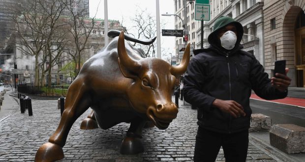 A man wearing a face mask takes a selfie at the Charging Bull statue near the New Stock Exchange. Photograph: Angela Weiss/AFP