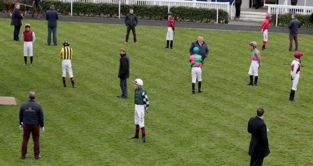Jockeys and trainers endeavour to maintain social distancing in the parade ring at Naas last Monday. Photograph:  Morgan Treacy/Inpho