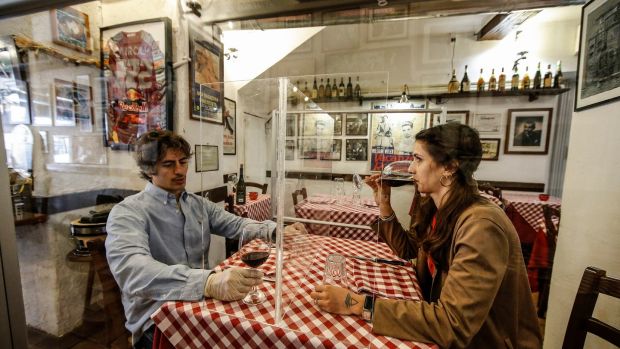 Valerio Calderoni, owner of an italian tipical restaurant, and his wife Martina, pose for a picture during a test for a of possible plexiglass separator between tables of restaurant ‘’Il Ciak’’, Trastevere district in Rome on Thursday. Photograph: Fabio Frustaci/EPA