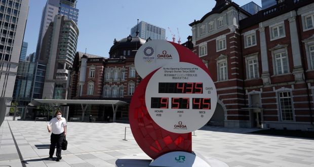 A commuter in Tokyo walks past a countdown clock for the opening ceremony of Tokyo 2020 Olympics, which was postponed to July 2021 due to the coronavirus pandemic. Photo: Kimimasa Mayama/EPA
