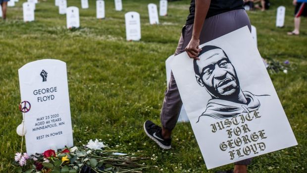 A person holds a placard with a portrait of George Floyd during a candlelight vigil at an installation created by Anna Barber and Connor Wright called Say Their Names to honor victims of police brutality on Sunday in Minneapolis, Minnesota. - Photograph: Kerem Yucel/AFP/Getty Images