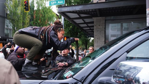 A protester stands on the hood of a truck during a confrontation with a Fox News television crew in Seattle, Washington. Photograph: Stephen Brashear/EPA