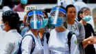 Parents wait as students wearing masks and face shields leave after attending classes during the first day of reopening of public high schools following closure due to the  coronavirus in Yangon on Tuesday. Photograph: Sai Aung Main/AFP