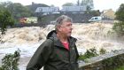 Patrick Guy at the back of his house at Riverside beside the Owenglin river as water pours down the waterfall after earlier flooding. Photograph: Joe O’Shaughnessy