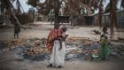 A woman holds her younger child while standing in a burned out area in the recently attacked village of Aldeia da Paz outside Macomia, Mozambique. Photograph:  Marco Longari/AFP