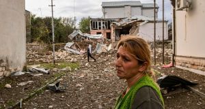 A woman stands in front of a destroyed house  in the Nagorno-Karabakh region’s main city of Stepanakert on Thursday, during the ongoing fighting between Armenia and Azerbaijan over the disputed region. Photograph: Aris Messinis/AFP via Getty Images