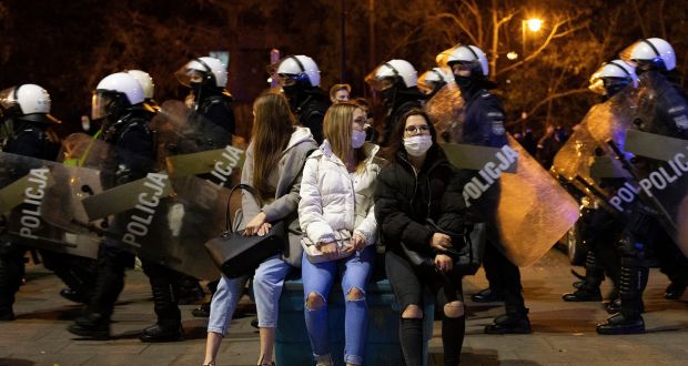 Women wearing face masks watch as police march past them, in Warsaw, Poland, amid protests at the weekend. Poland’s right-wing government has delayed implementation of a court ruling that would impose a near-total ban on abortions after two weeks of the largest protests the country has experienced since the 1989 collapse of communism. File photograph: Maciek Nabrdalik/New York Times