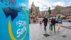 Pedestrians walk past Covid-19 informatin signs in Belfast over the weekend.  Photograph: Getty 