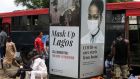   People walk past a   billboard advertising ‘Mask up Lagos’ along a road in Yaba district in Lagos, Nigeria. Photograph:Akintunde Akinleye/EPA