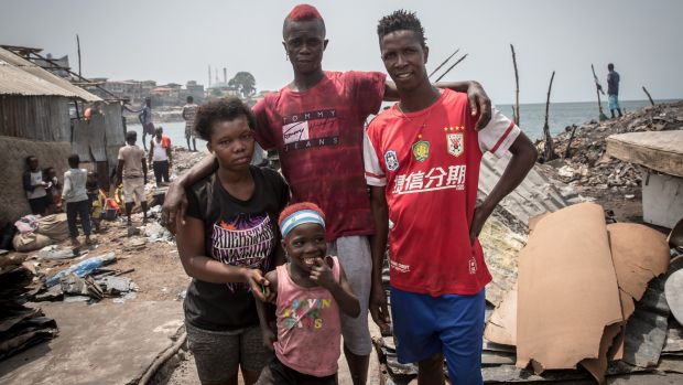 Idrissa Turay stands with his brother, wife and child on the site where their home used to be, in Susan’s Bay, Freetown. Photograph: Sally Hayden