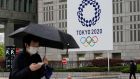 People walk past a banner with the logo of the Tokyo 2020 Olympic Games hanging from the wall of the Tokyo Metropolitan City Hall. Photograph: Kimimasa Mayama/EPA
