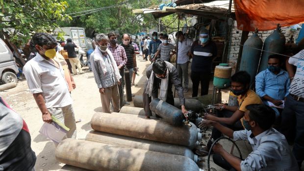 People stand in queues to refill oxygen cylinders in New Delhi on Friday. Photograph: AP