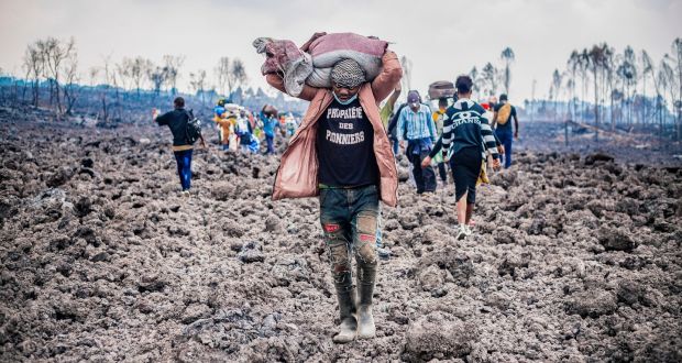  A Congolese porter helps people evacuate across cooled lava from the town of Goma in the aftermath of the eruption on May 26th. Photograph: Michel Lunanga/EPA