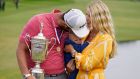 Jon Rahm holds the US Open trophy as he stands with his wife, Kelley and their child, Kepa. Photograph: Marcio Jose Sanchez/AP