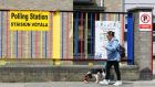 A woman walks a dog past a polling station at St Patrick’s Girls National School, Ringsend, Dublin. Photograph: Brian Lawless/PA Wire