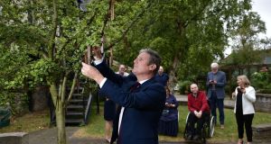 British Labour party leader Keir Starmer hangs a message on the Tree to Remember Jean McConville at the Wave Trauma Centre in Belfast watched by victims of The Troubles. Photograph: Charles McQuillan/PA Wire 