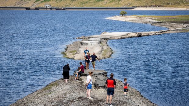 People walk along a pathway exposed by the falling water level at Spelga Reservoir in the Mourne Mountains of Co Down. Northern Ireland Water has asked the public to reduce water use as the system is under extreme pressure due to an increase in demand. Photograph: PA