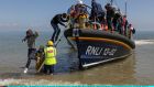 A group of around 40 migrants arriving via the RNLI (Royal National Lifeboat Institution) on Dungeness beach, England. Photograph:  Dan Kitwood/Getty Images