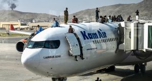 People climb atop a plane as they wait at the airport in Kabul to flee Afghanistan. Photograph:  Wakil Kohsar/AFP/Getty Images