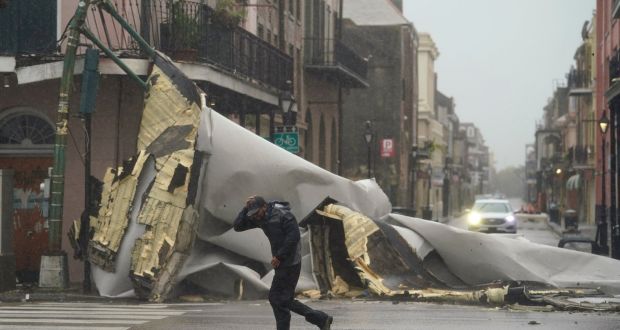 A man passes by a section of roof that was blown off of a building in the French Quarter by Hurricane Ida winds. Photograph: Eric Gay/AP Photo