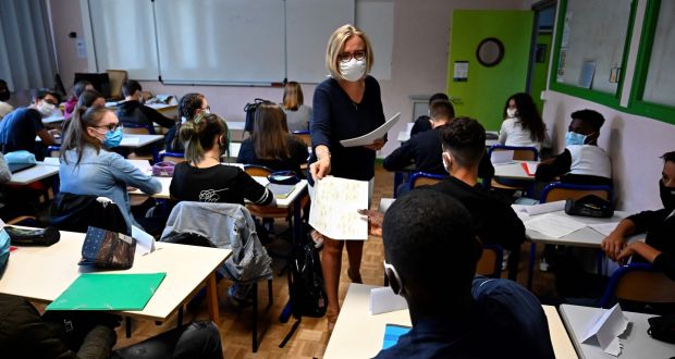 A teacher with a protective mask distributes documents to pupils in a  school in Rennes, western France. Photograph: Damien Meyer/AFP via Getty Images