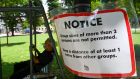 A man resting in a park in Singapore next to a Covid social distancing notice. Photograph:  Roslan Rahman/AFP via Getty Images