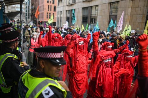 REAL PROGRESS NOW: Extinction Rebellion's Red Brigade at a demonstration outside JP Morgan bank in Glasgow, Scotland. Many climate action groups have taken to the streets near where the Cop26 summit is taking place to demand real progress in reducing carbon emissions, cleaning up oceans and reducing fossil fuel usage worldwide. Photograph: Peter Summers/Getty
